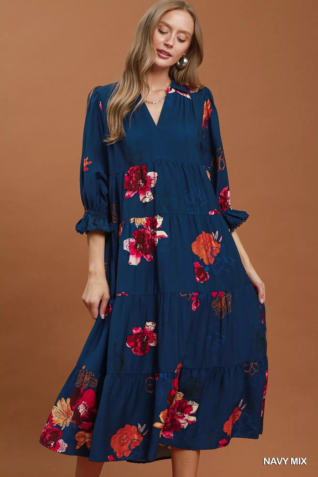 Woman wearing a navy blue dress with floral patterns on a brown background